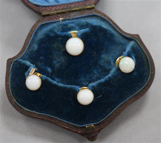 A cased early 20th century four piece yellow metal and white opal dress stud set.